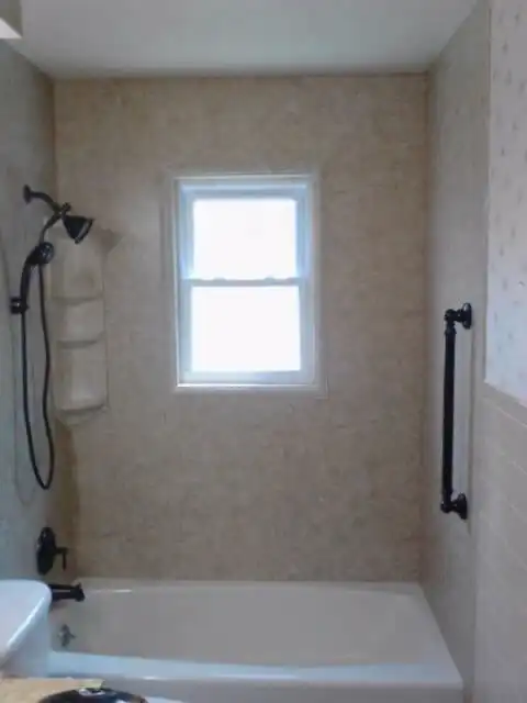bath shower with black shower head and a black shower grab bar