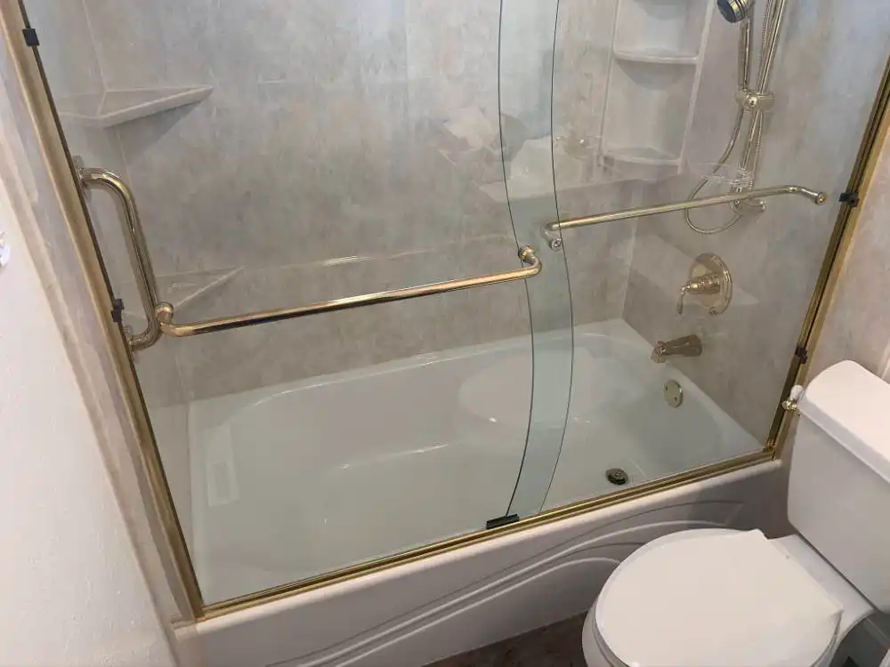 sliding glass shower door enclosure with gold accents