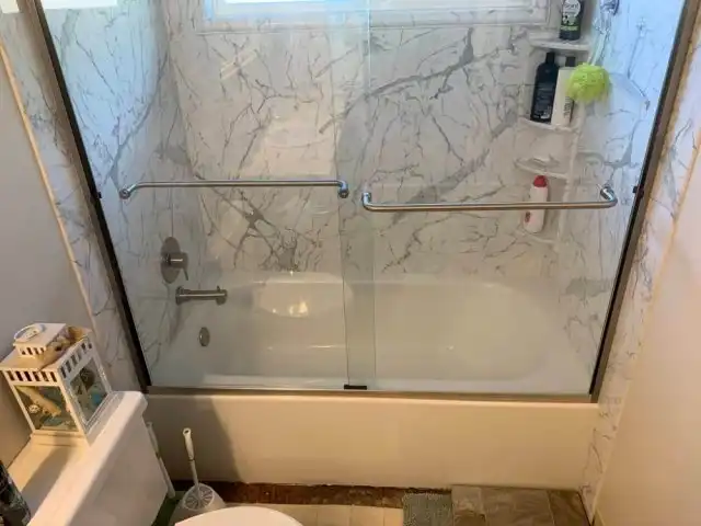 bath/shower combo with sliding glass door and marble walls
