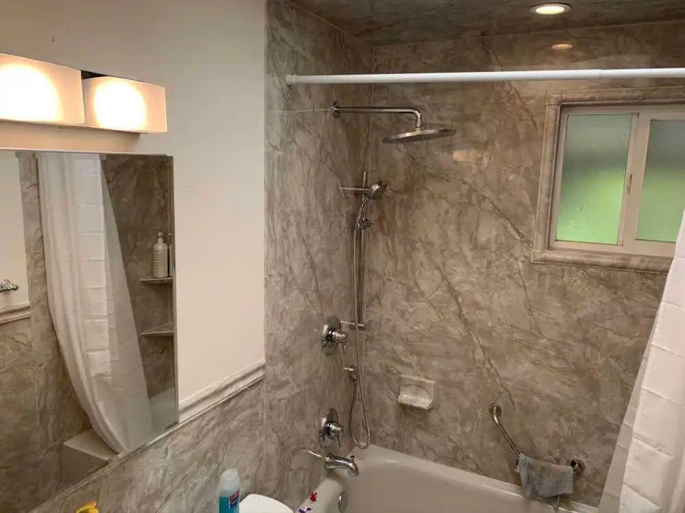 bathroom remodel with marble walls and shower bath combo with waterfall shower