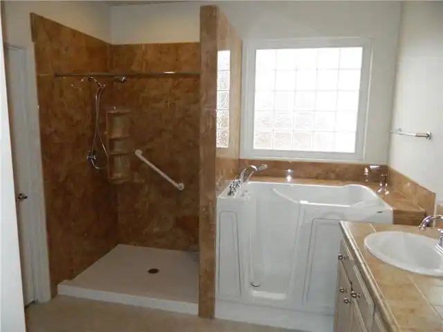 accessible walk in bathtub next to a marble shower enclosure